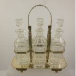 A SILVER PLATED DECANTER STAND with three cut glass spirit decanters, swing handle, raised on paw