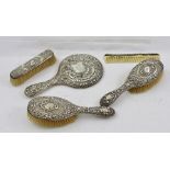 AN EDWARDIAN EMBOSSED SILVER MOUNTED FIVE PIECE DRESSING SET, includes hand mirror, comb and