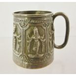 A FAR EASTERN WHITE METAL TANKARD, the panels embossed with dancing figures, the handle floral