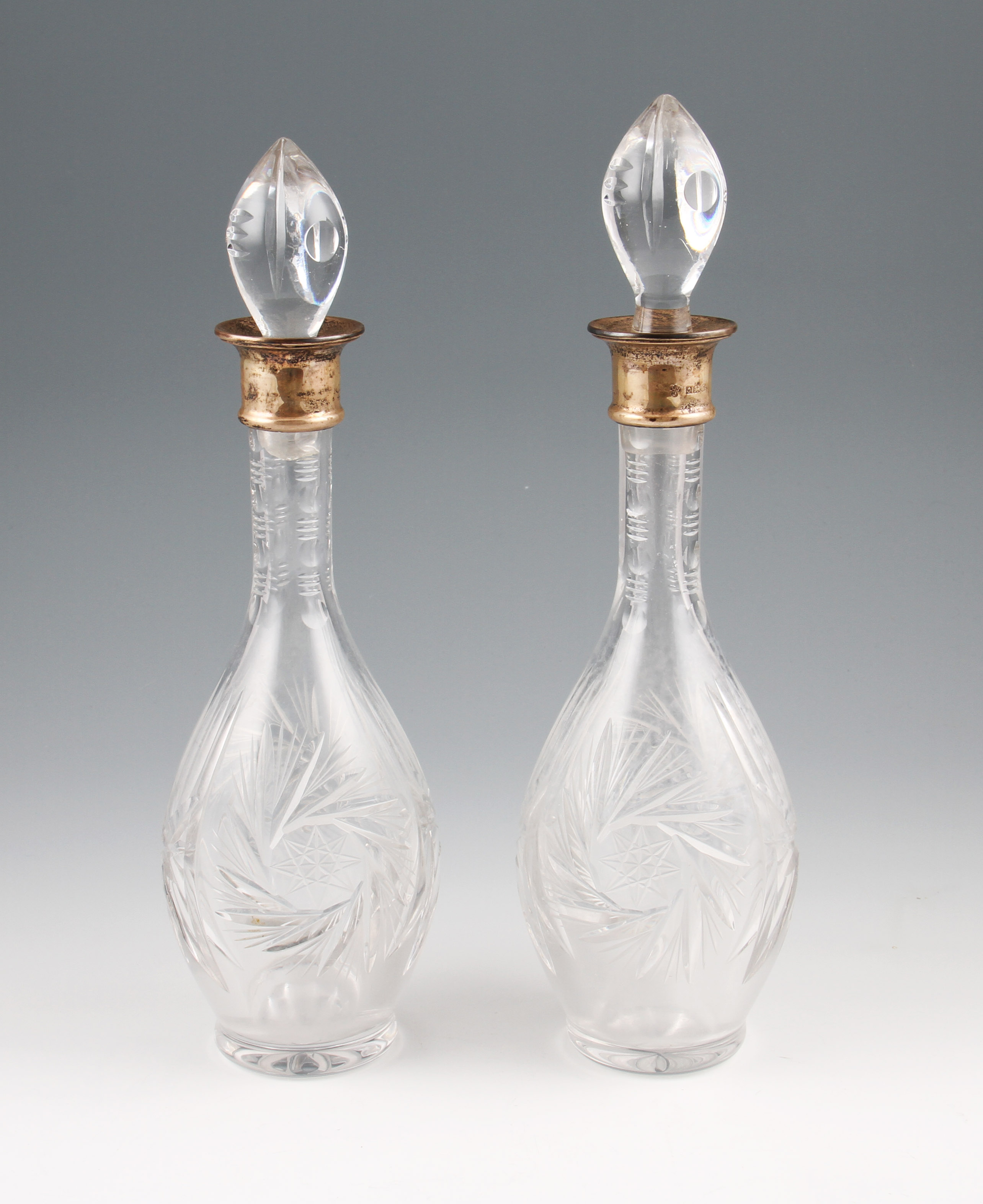A pair of cut glass decanters with stoppers, both having silver collars, hallmarked Birmingham