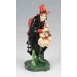 A Royal Doulton figure ‘The Mask Seller’ HN 1361, dressed in black, orange and green on a green