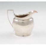 A George III silver cream jug, of oval form with engraved foliage frieze to upper and lower body,