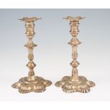A matched pair of George II silver candlesticks, each having removable sconces of shell design,