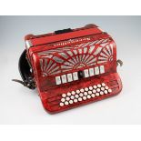 A Serenellini button accordion with red pearl design finish, fitted with 33 buttons over three