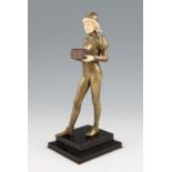 An early 20th Century bronze and ivory figure depicting a page boy carrying a casket, on a stepped