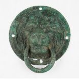 An ancient Roman circular hollow cast bronze door knocker in the form of a lion mask with circular