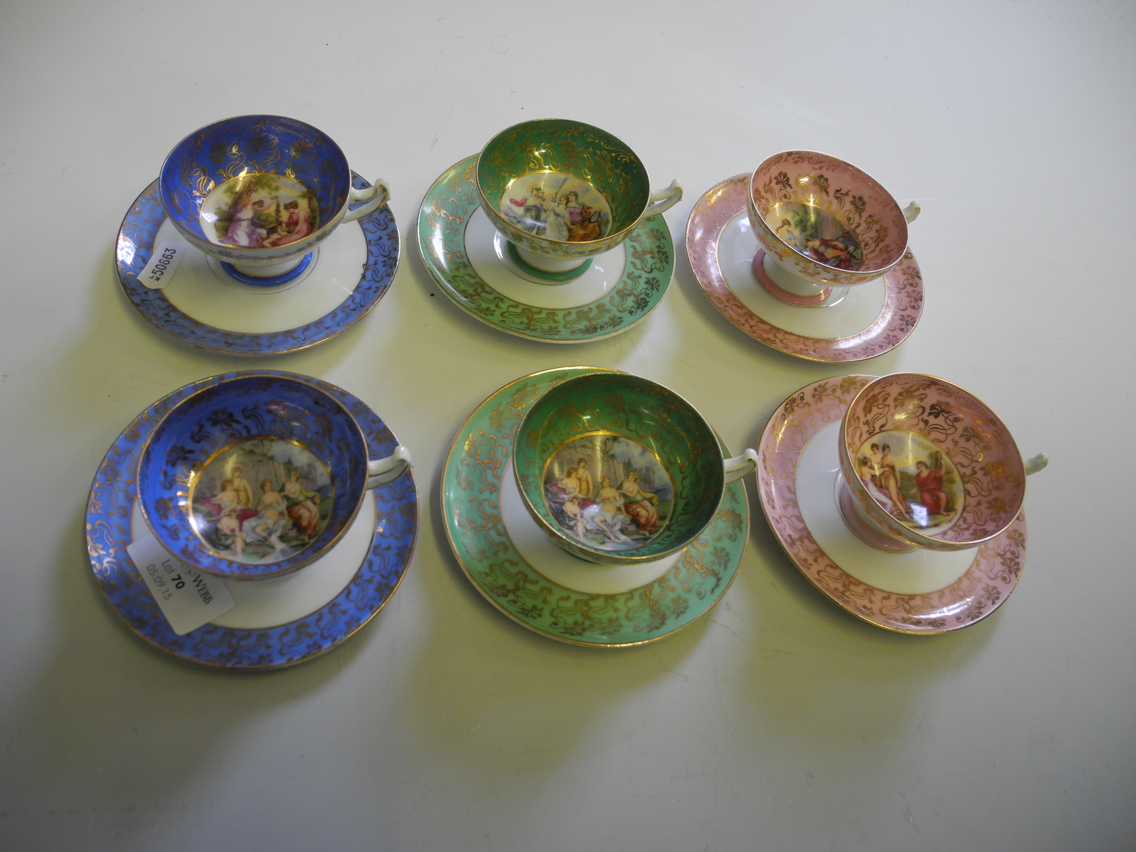 A set of pink, blue, green and gilt cups and saucers with classical scenes.