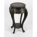 An early 20th Century Chinese ebony style two tier plate / jardinière stand with carved skirts and