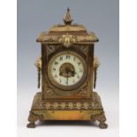 An early 20th Century brass mantel clock with lion head bust handles to sides with scroll design