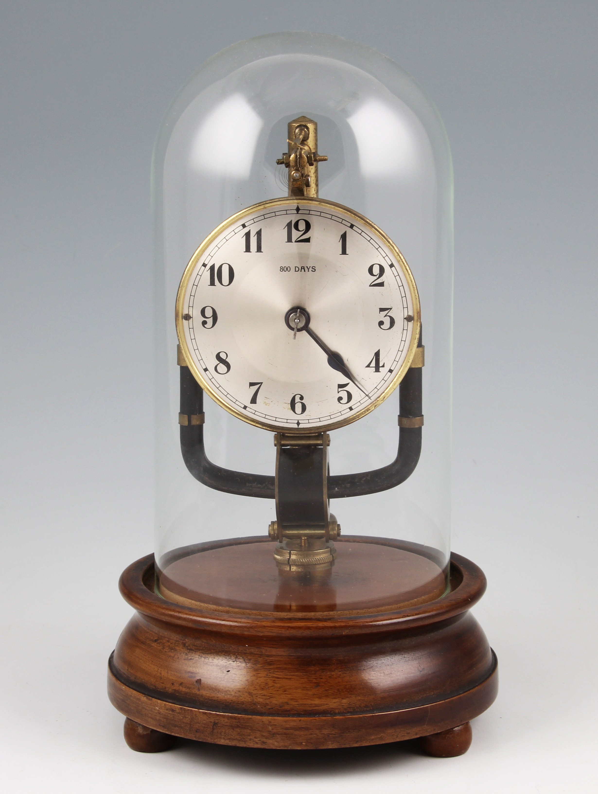 An early 20th Century 800 day magnetic clock, on circular turned mahogany stand with domed glass