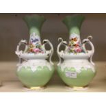 A pair of green and white decorative flower vases with painted floral detail.