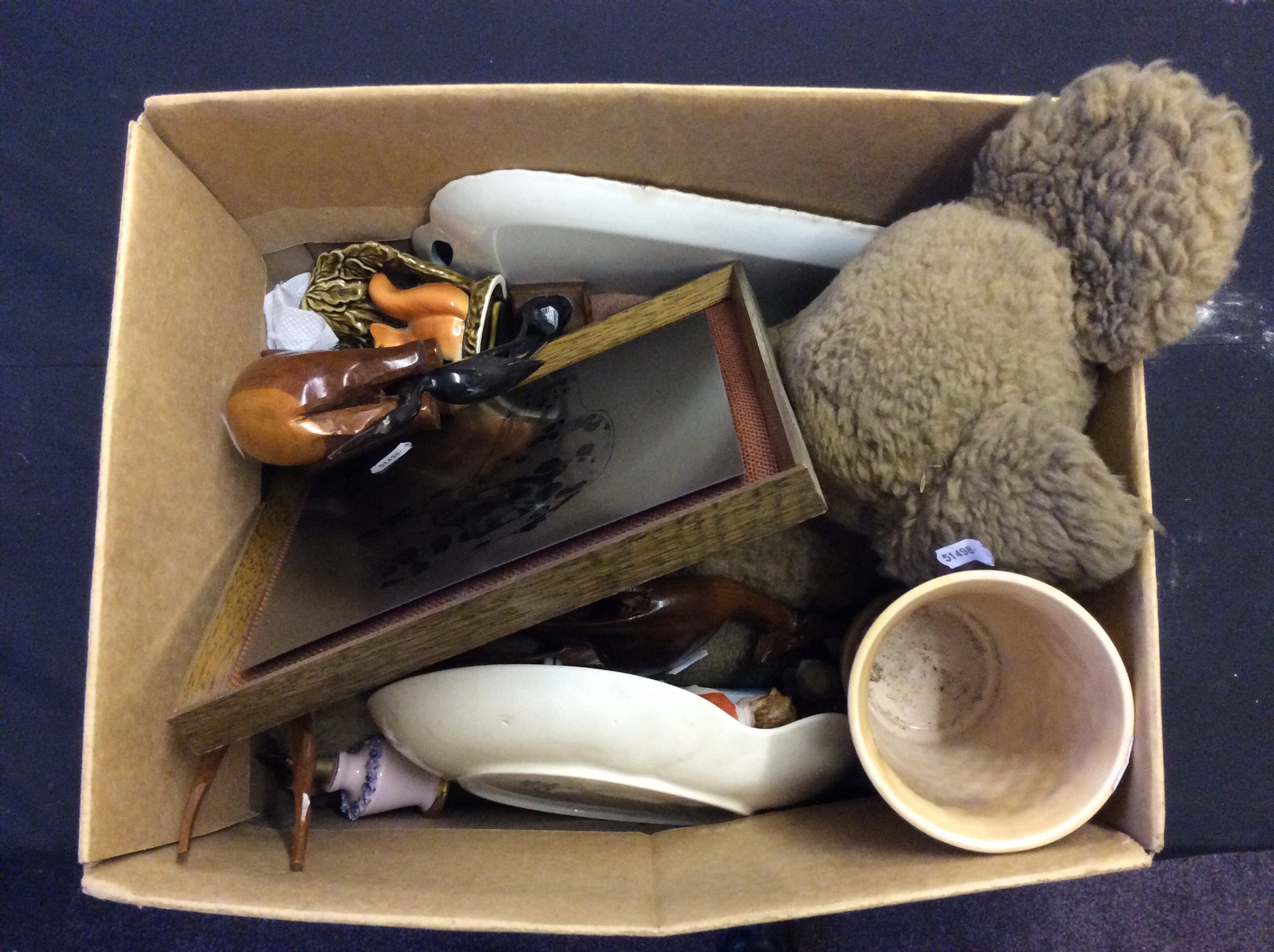 A box of various household items including a teddy bear, a ceramic vase and dish and a set of wooden