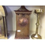 An Arts and Crafts style mantle clock with copper face on wooden base.