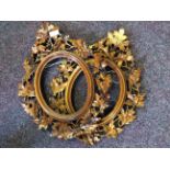 A pair of carved wooden oval picture framed with oak leaf and acorn decoration.