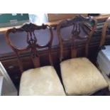 Three mahogany dining chairs with carved backs and gold coloured upholstered seats.