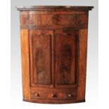 A 19th century mahogany bow front two door corner cabinet with raised paneled decoration doors