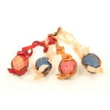 Four pincushions formed from halves of natural walnuts, linked by coloured ribbons and bows,