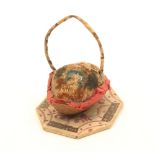 An unusual pincushion in the form of a basket, modelled from a walnut shell and mounted on a painted