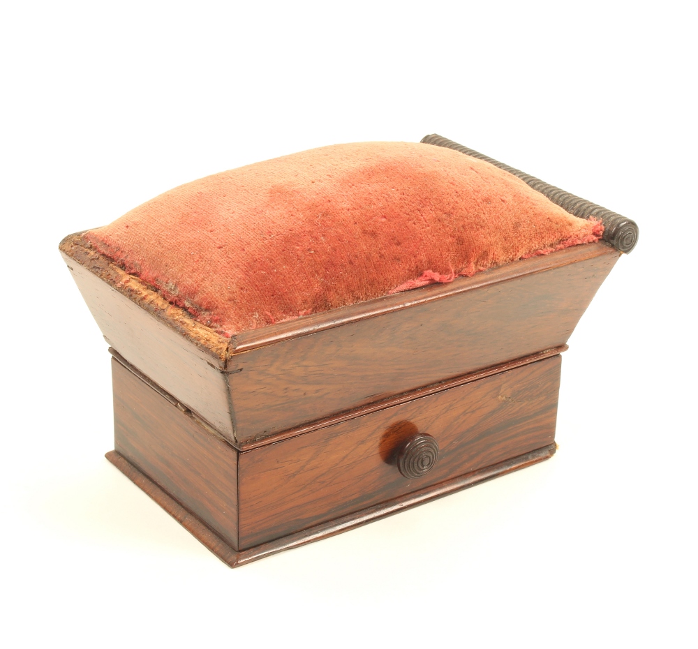 An early 19th century rosewood table pincushion of sarcophagus form, the base fitted with a