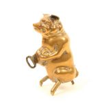 A brass novelty tape measure in the form of a seated pig, printed tape in inches and centimetres,