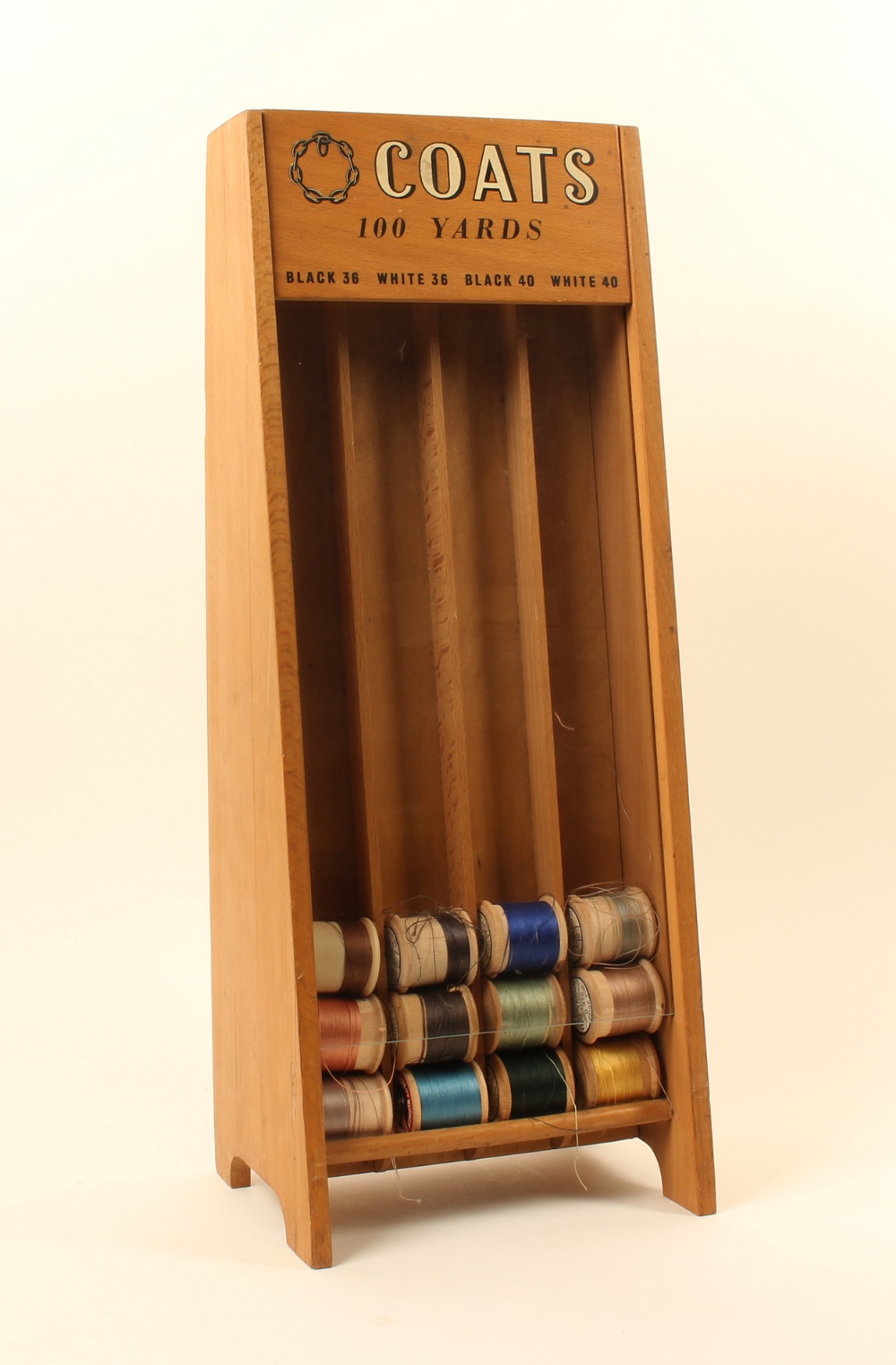A Coats cotton reel counter display stand, with four reel slots below a panel inscribed "Coats 100