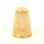 A 19th century gold thimble of plain form, over a raised and decorated rim.(From The Collection Of