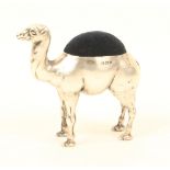 An Edwardian novelty silver pincushion in the form of a camel, with a dark blue velvet cushion, by