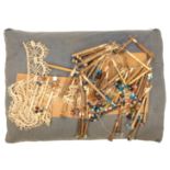 A lacemaker's pillow with work in progress, with a selection of wooden lace bobbins, three named