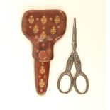 A pair of steel bladed scissors with tooled leather case, blades indistinctly stamped, leaf
