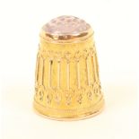 A gold thimble with stone top, the sides with raised wirework decoration over a raised rim,