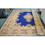 A Kirman Carpet of medallion design in beige on a blue field and bordered, 13' 8" (420cms) x 10' (