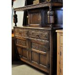 An antique design oak Court Cupboard enclosed by panelled door and with baluster turned pilasters,