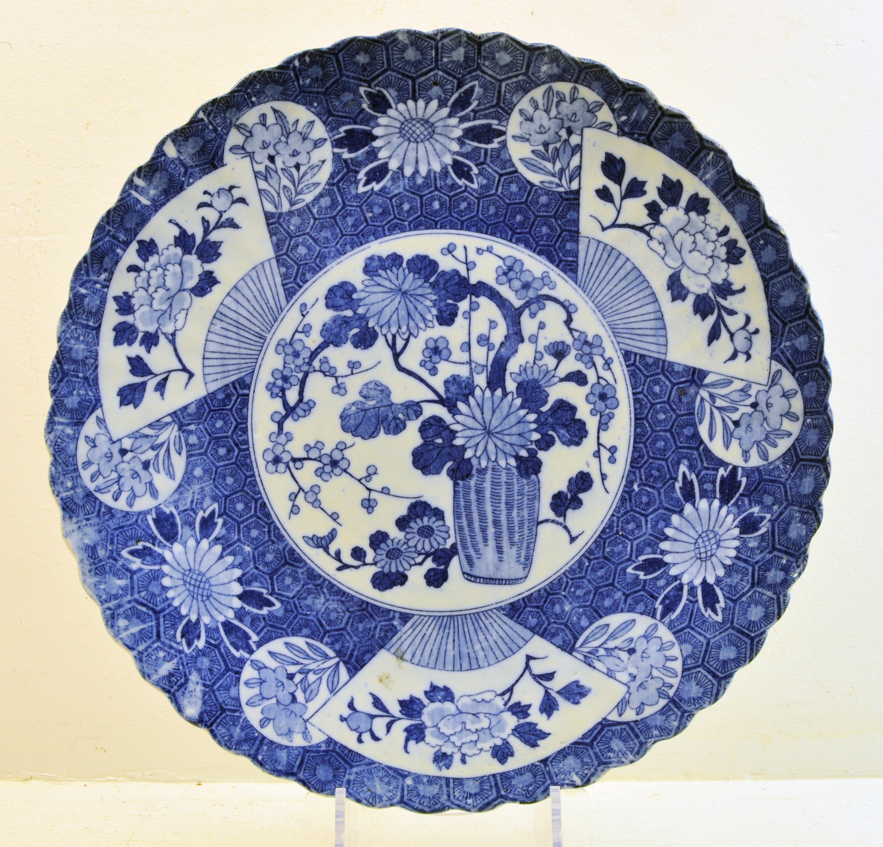 A Japanese Plate decorated in blue and white with a centre flowering shrub and fan pattern border,