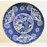 A Japanese Plate decorated in blue and white with a centre flowering shrub and fan pattern border,