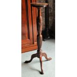 A mahogany Torchere with leaf carved base, turned column and triple splay supports.