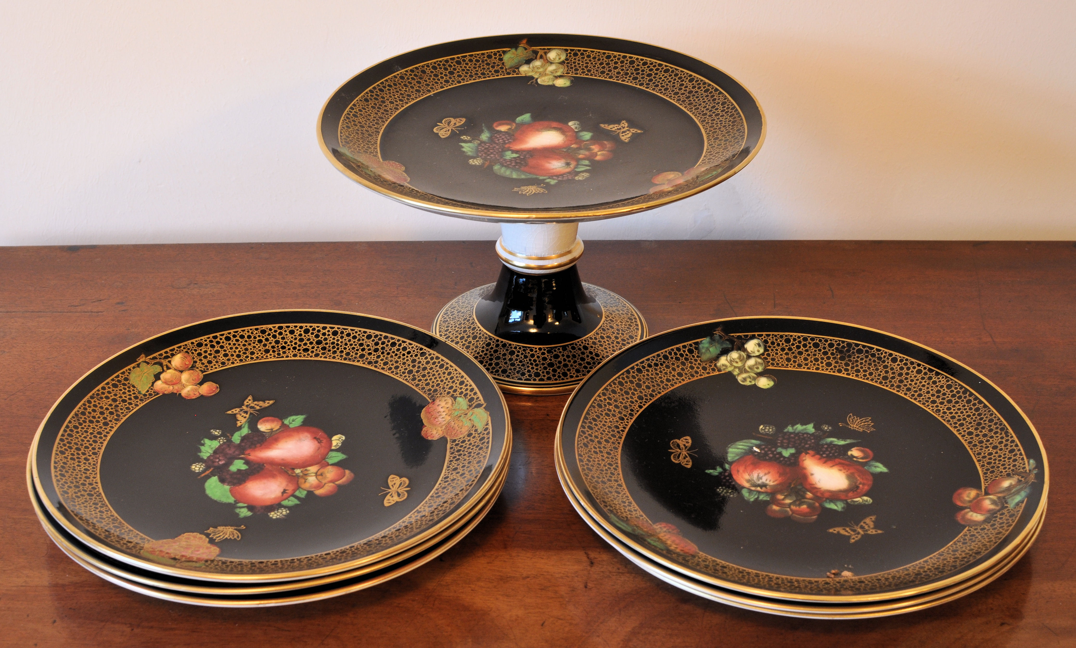 A Solian ware Dessert Service decorated with fruit on a black ground within a gilded border with