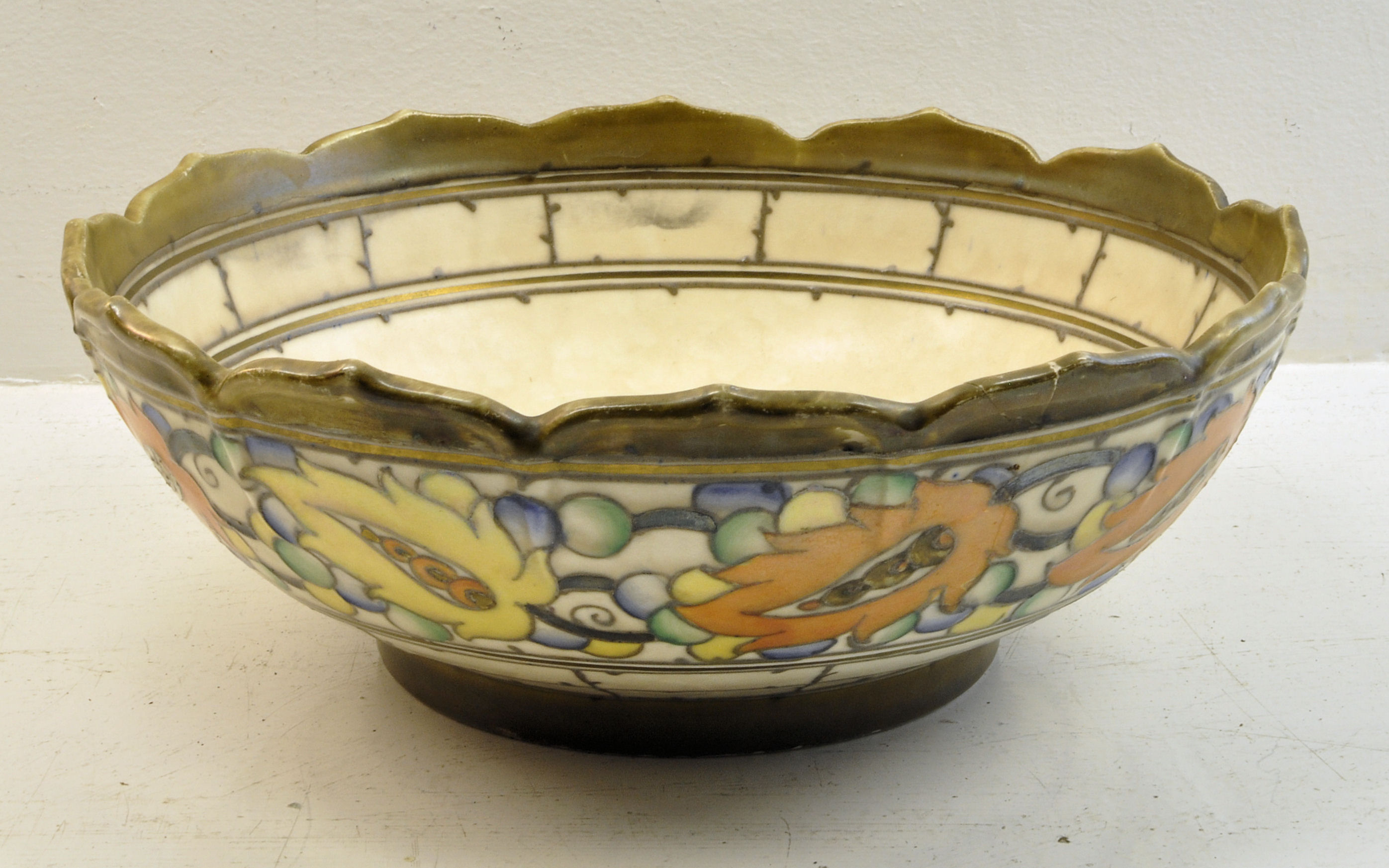 A Crown Ducal Bowl by Charlotte Rhead, decorated with a continuous band of flowers and leaves in