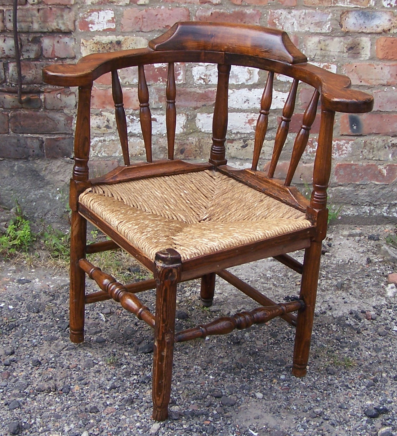 An 18th century design elm frame Corner Chair with spindle turned back, rush seat and turned