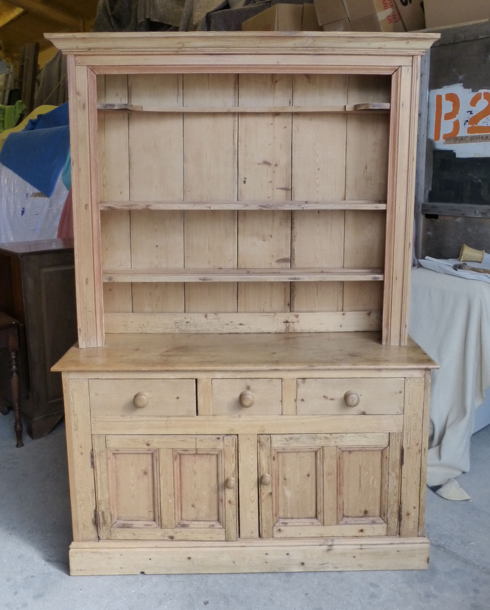 A pine Dresser with boarded canopied Plate Rack, the base with three frieze drawers, two cupboards