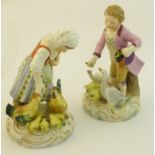 A pair of continental Figures of a boy and girl feeding poultry on rococo style gilt bases, each