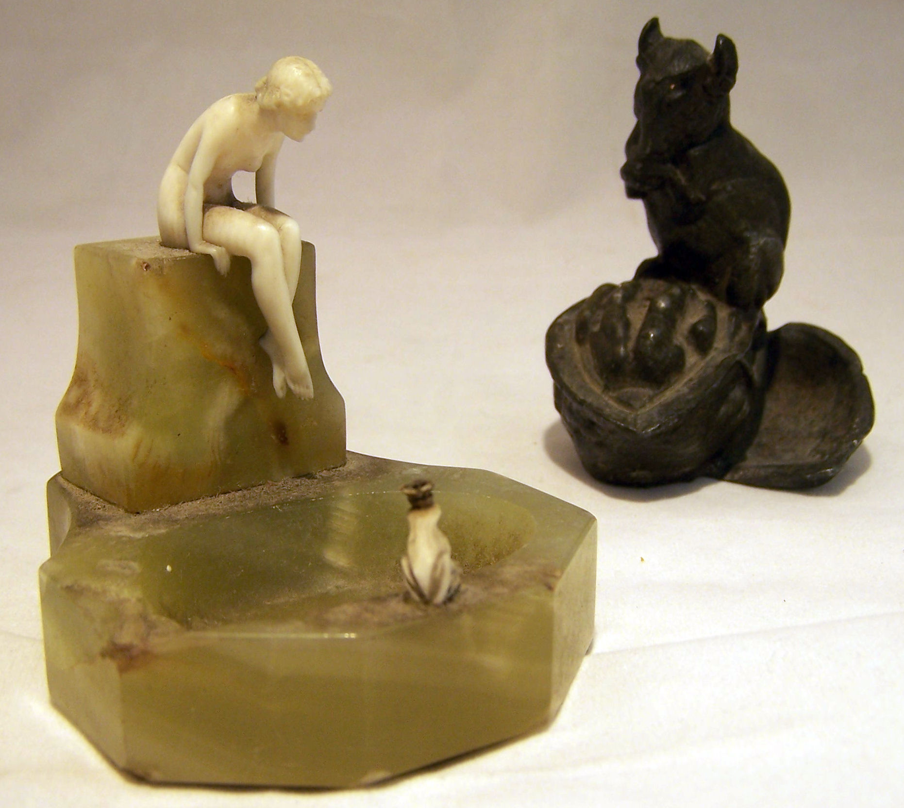 An onyx Ashtray surmounted by a nude ivory female figure and a crowned frog, 3" (7cms) high (