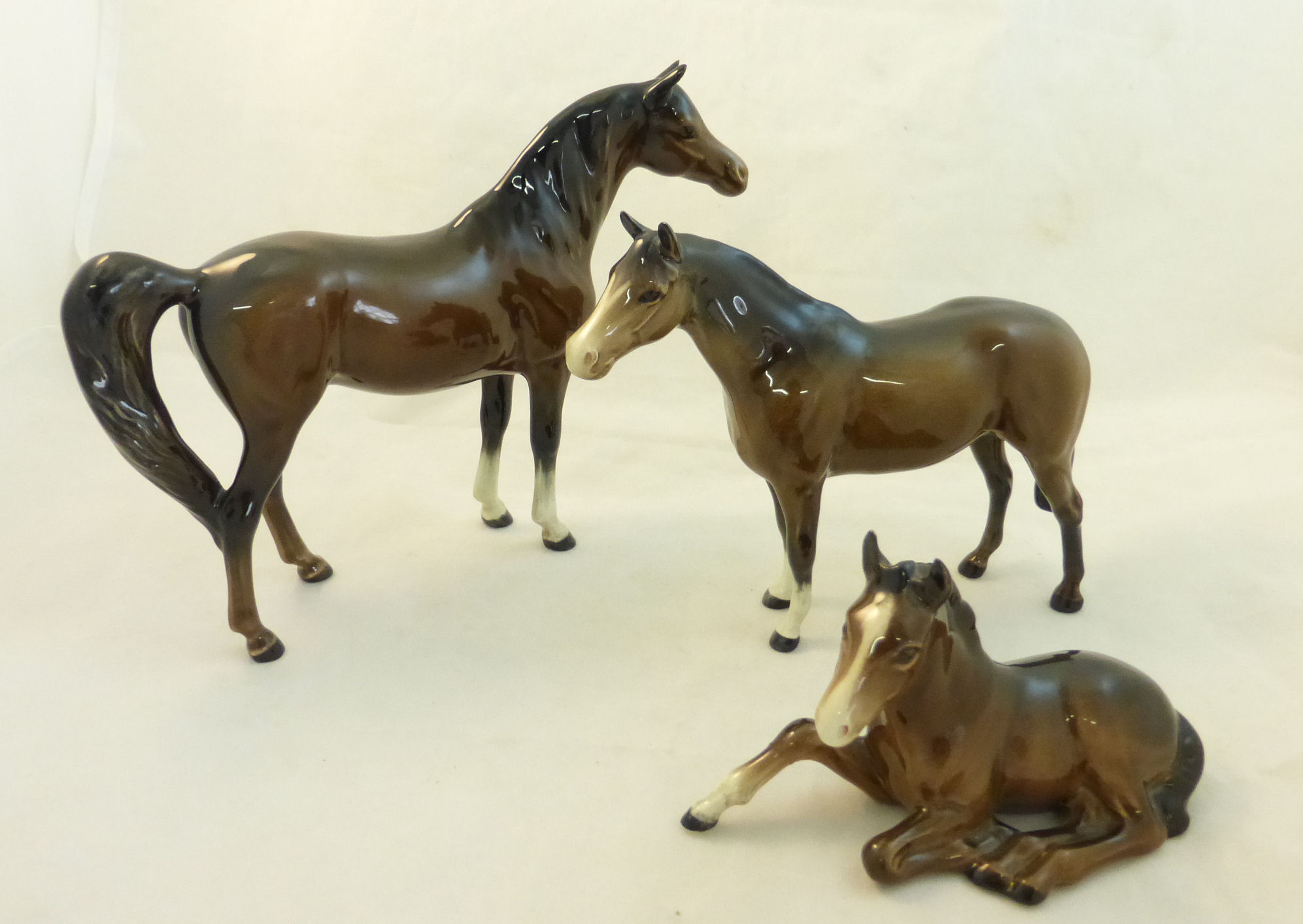 A Beswick Model of a brown Arab Horse, a brown thoroughbred Stallion and a brown Foal lying down.