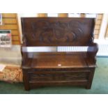 A carved oak Monk's Bench with folding table top, box seat and stile supports, 3' 6" (107cms) wide.