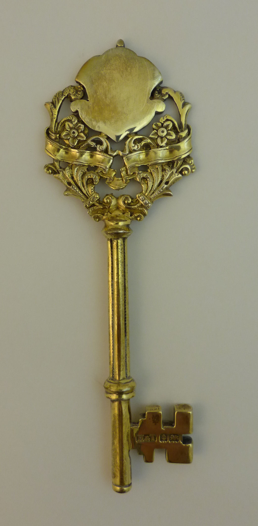 A silver gilt Presentation Key, the finial with blank shield and scrolling flower decoration,