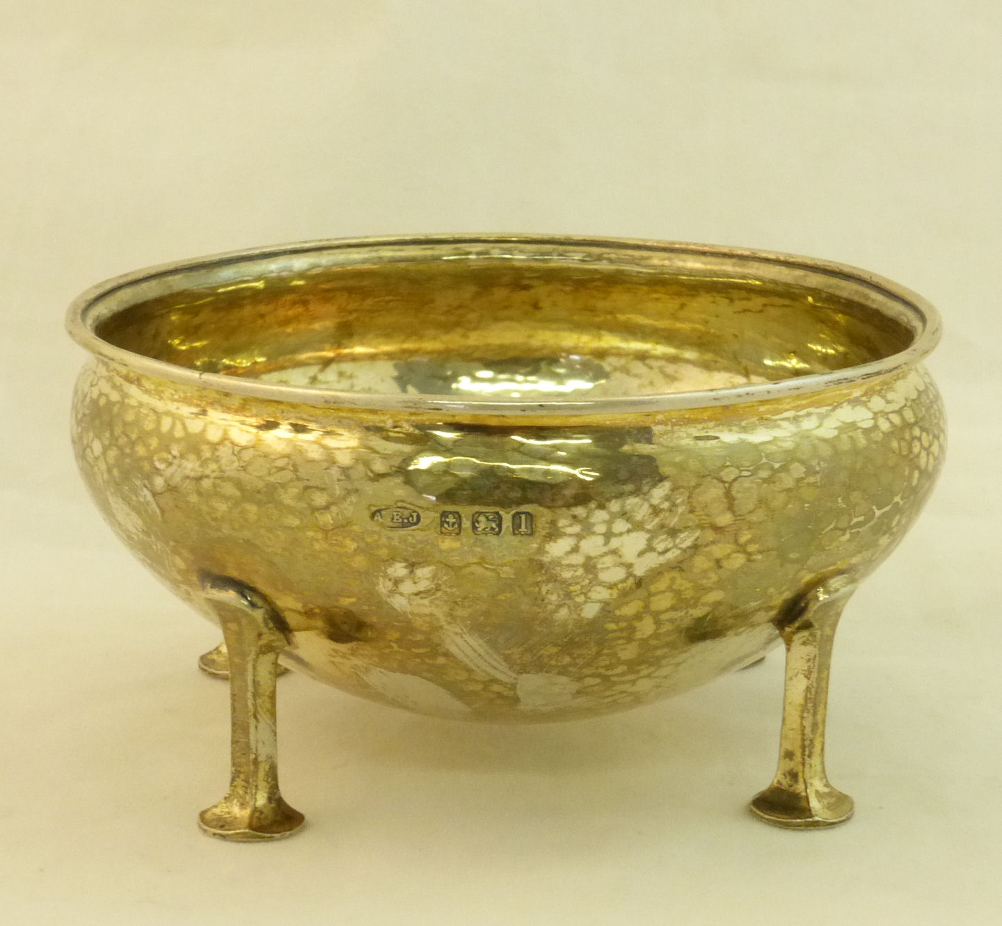 A silver Bowl of hammered circular form on four stylised legs, Birmingham 1910, maker: A E Jones,