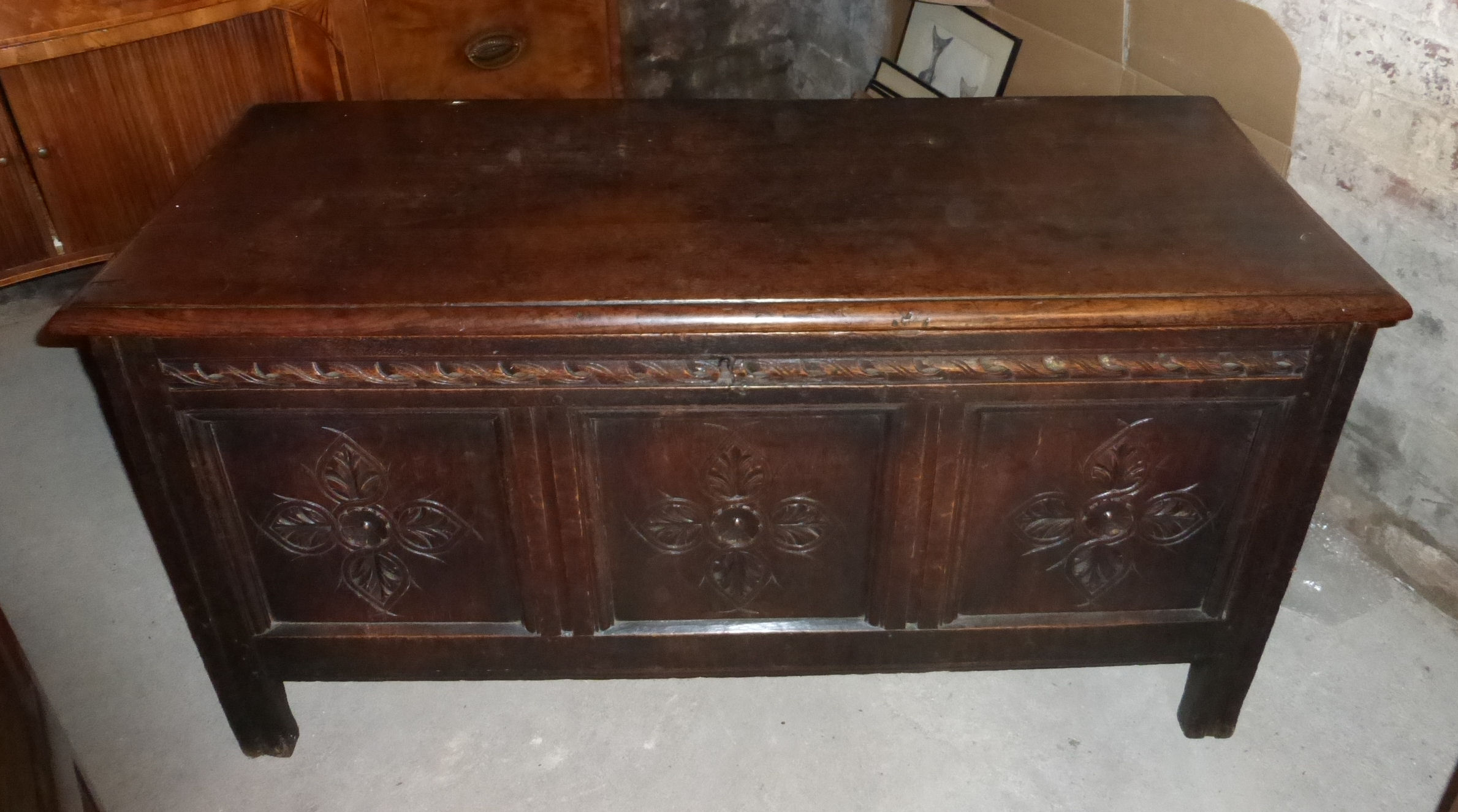 An 18th century oak Coffer with plain hinged lid, the triple panel front with stylised floral
