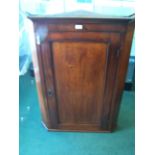 An early 19th century mahogany Corner Wall Cupboard with stepped cornice, enclosed by a single