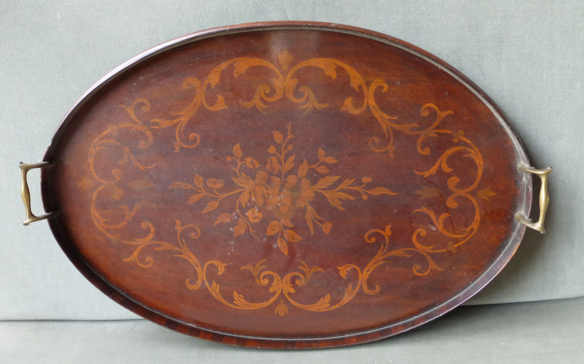 An Edwardian mahogany oval two handled Tray inlaid with floral marquetry and with brass handles, 23"