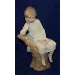 A Lladro Figure of a seated child reading a book, 8" (20cms) high.