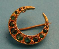 An Edwardian 9ct gold and emerald crescent shaped brooch.
